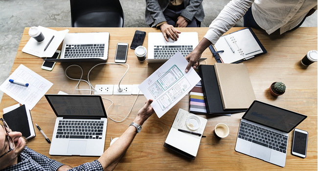 office workers with their laptops out in a boardroom meeting